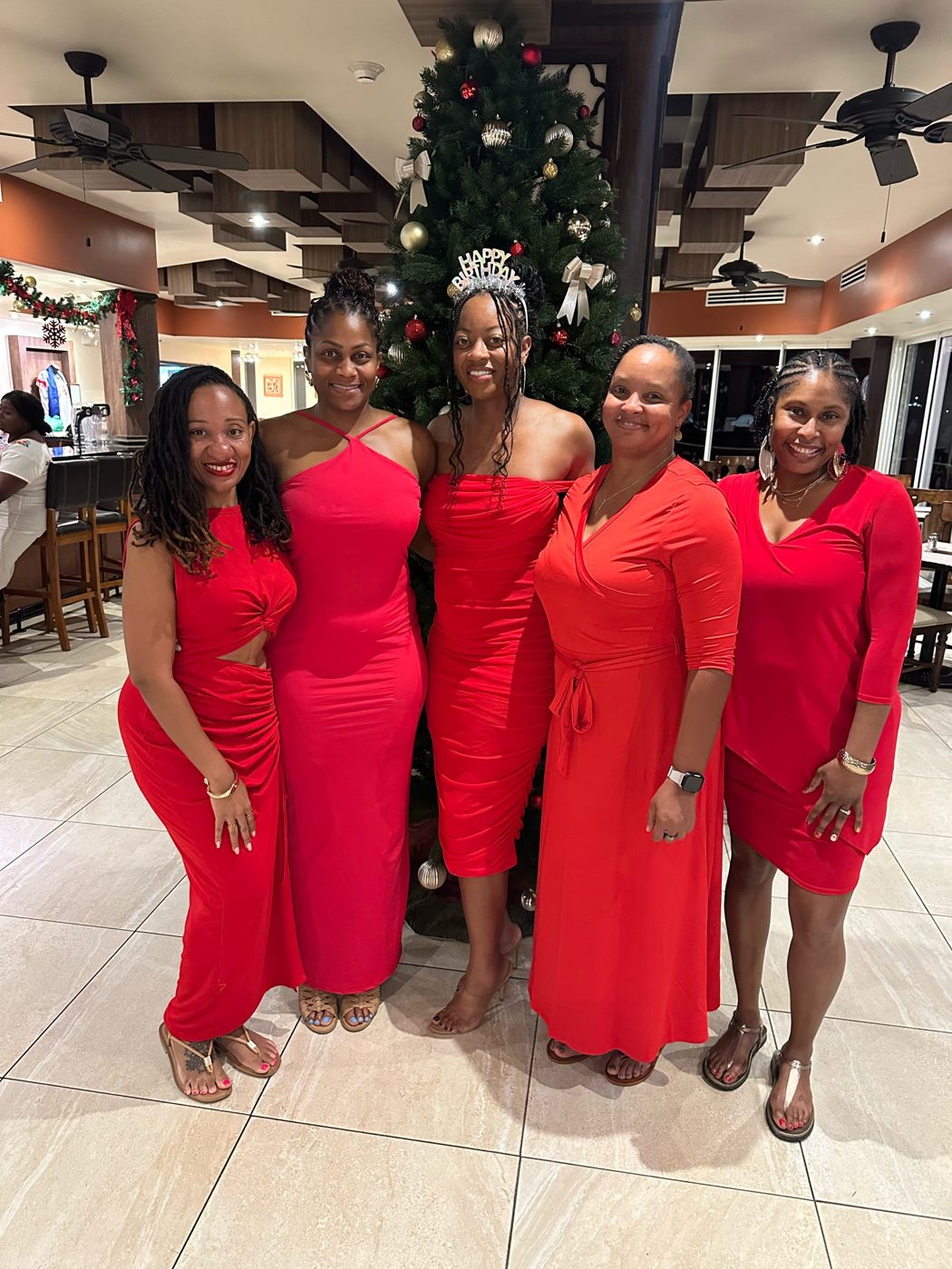 Five travelers in matching red dresses celebrating a birthday
